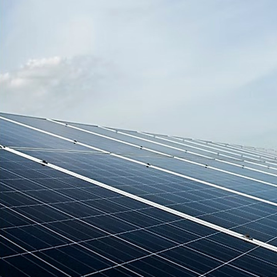 Fileiras de módulos fotovoltaicos vistas de perto contra o céu